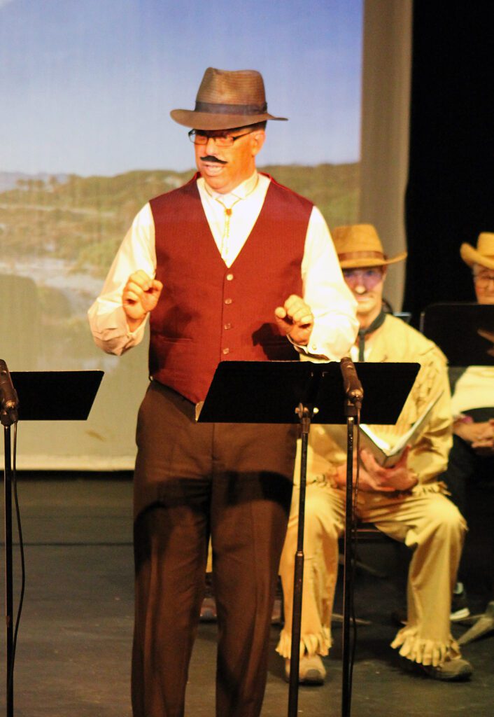 A man in a red vest and hat is on stage