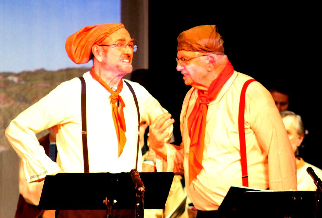 Two men in orange hats and ties are talking.